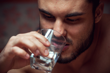 Young drunken man with glass of vodkaの写真素材