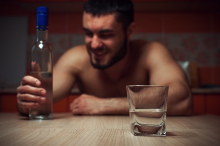 Angry depressed alcoholic man sitting at homeの写真素材
