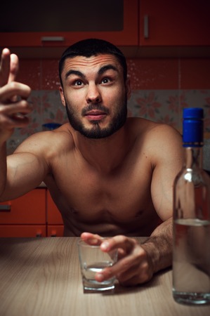 Young caucasian man drinking alcohol at homeの写真素材