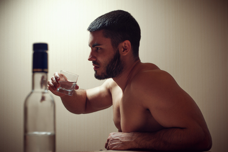 Young caucasian man drinking alcohol at homeの写真素材