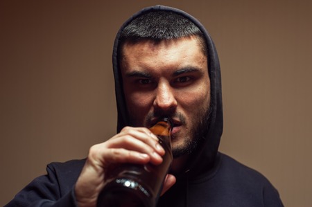 Portrait of young depressed man drinking beerの写真素材