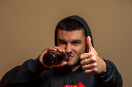 Young man drinking beer and showing thumbs upの写真素材