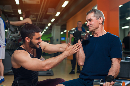 Personal trainer working with senior man in gymの写真素材