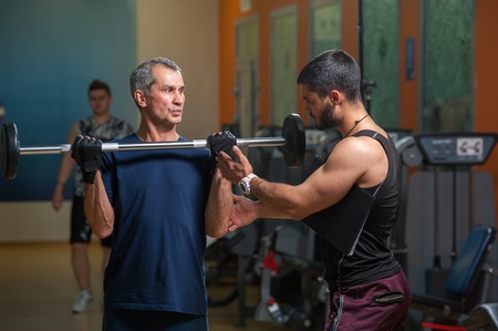 Personal trainer working with senior man in gymの写真素材