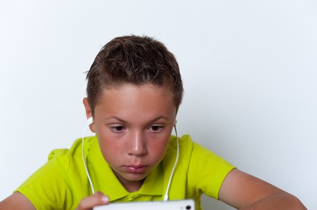 Pensive tween wearing earphones with smartphoneの写真素材