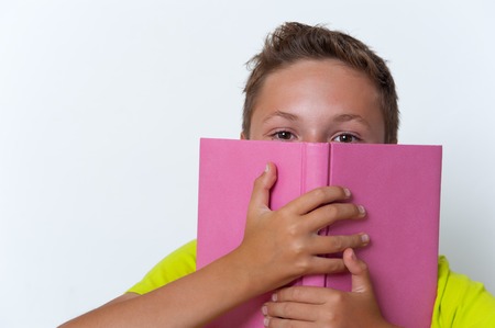 Tween boy covering his face with the book.