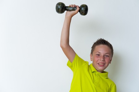 Happy smiling tween boy lifting dumbbellの写真素材