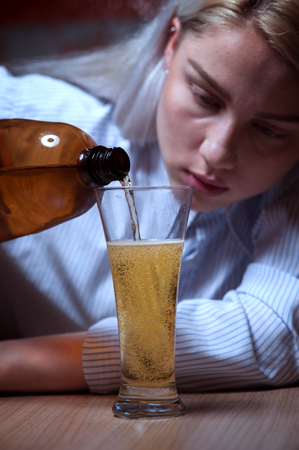 Young woman drinking beer alone at homeの写真素材