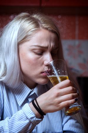 Sad depressed female drinking beer alone at home