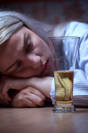 Young woman drinking beer alone at home