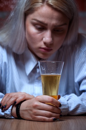 Young woman drinking beer alone at homeの写真素材
