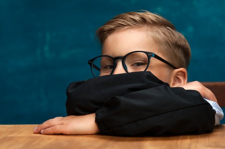 Smiling businessman child sitting at the tableの写真素材