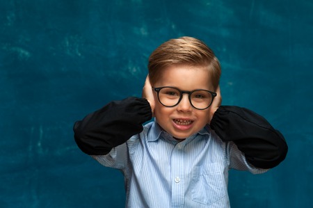Smiling boy with eyeglasses on blue backdropの写真素材