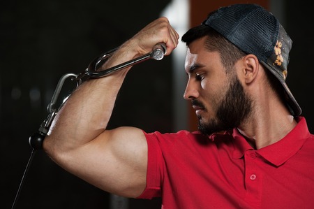 Handsome fitness model showing biceps muscles