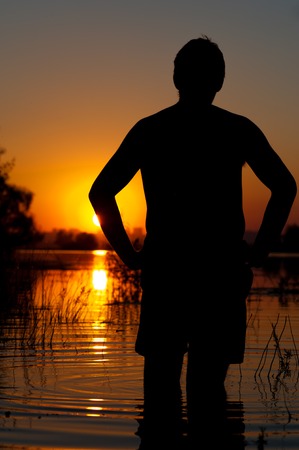 Silhouette of relaxed man on river or lake waterの写真素材