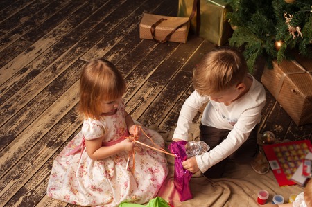 Adorable children sitting next to Christmas treeの写真素材