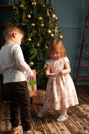 Kids opening Christmas gifts next to treeの写真素材