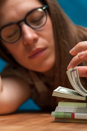 Young woman counting money heaps on the tableの写真素材