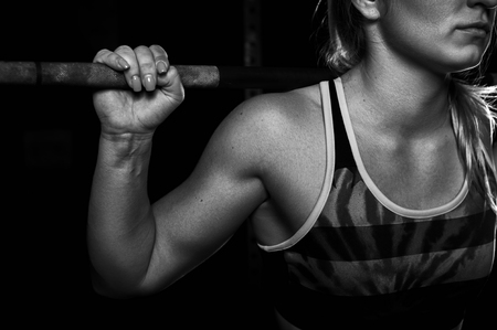 Closeup of female exercising with barbell in gymの写真素材