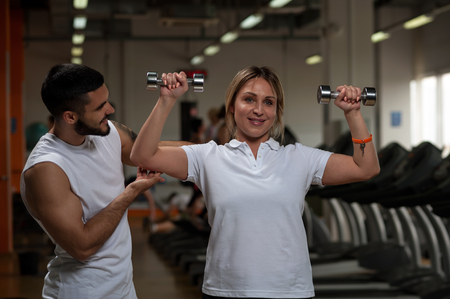 Personal coach with middle aged female in gym