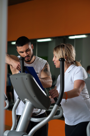 Middle aged woman working out with coach in gymの写真素材