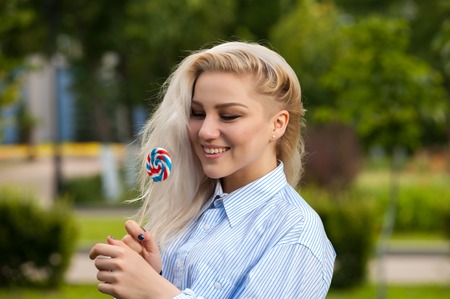 Portrait of attractive blonde female with candyの写真素材