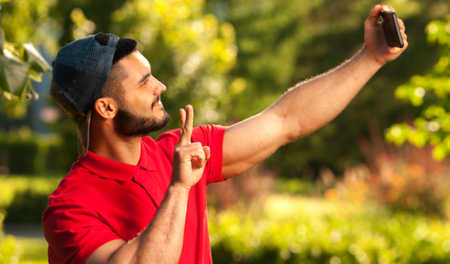 Young cheerful man making selfie picture in parkの写真素材