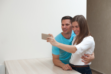 Positive young couple hugging and making selfieの写真素材