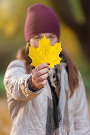 Young woman in knitted hat with yellow leafの写真素材