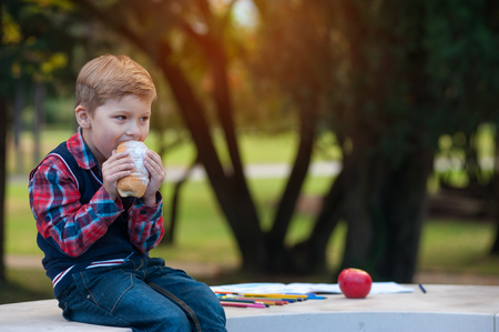 Portrait of a cheerful boy eating fresh croissantの写真素材
