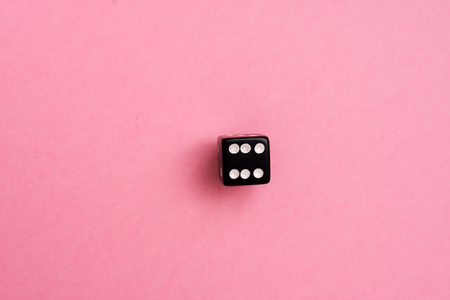 Black gaming dice on pink backgroundの写真素材