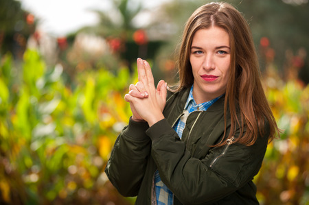Young woman folded her arms in form of a pistol