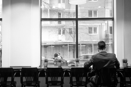 Young man in a formal suit sits at table in a cafeの写真素材