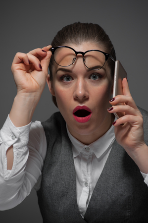 A surprised young woman is talking on the phoneの写真素材