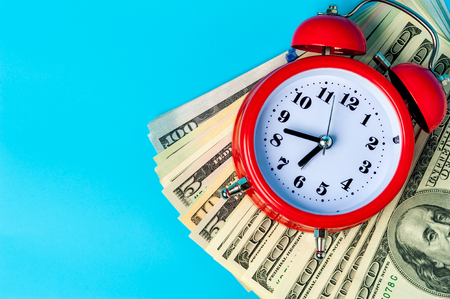 Red retro styled alarm clock on heap of american dollars.の写真素材
