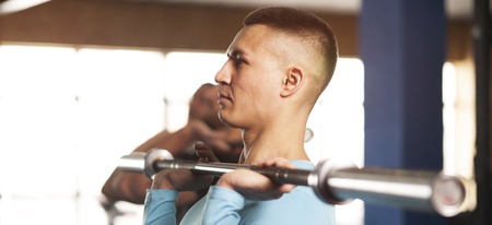 Young People in Gym Training With Barbells