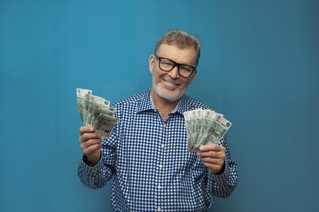 Elderly man in eyeglasses holding fan of rublesの写真素材