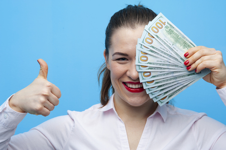 Portrait of young joyful woman holding american dollars billsの写真素材