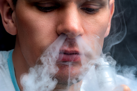 Close-up - young man vaping e-cigarette