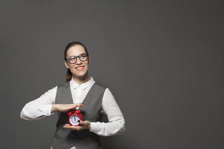 Portrait of charming businesswoman holding red vintage clockの写真素材