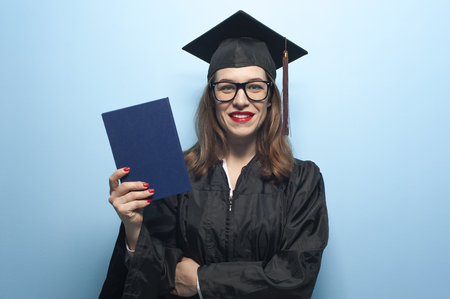 Graduate female student with stubble in eyeglasses wearing black mantleの写真素材