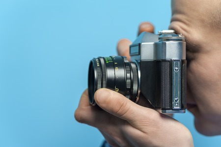 Side view of a young male photographer using vintage cameraの写真素材