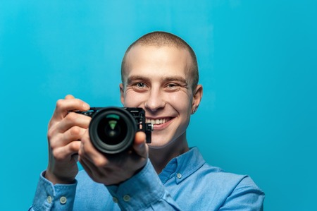 Portrait of positive young male photographer holding cameraの写真素材