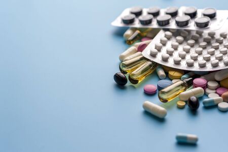 Blisters of pills and different capsules on blue background