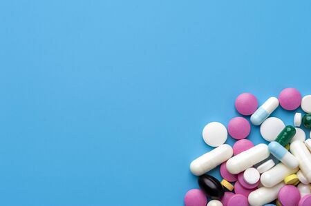 Flat lay - multicolored pills, drugs and capsules on blue background