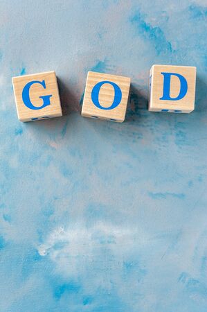 Wooden cubes with word GOD on blue table.