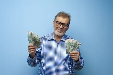 Happy elderly man in glasses holds banknotes