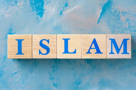 Wooden cubes with word ISLAM on blue table.の写真素材