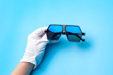Hands in gloves are holding beautiful sunglassesの写真素材