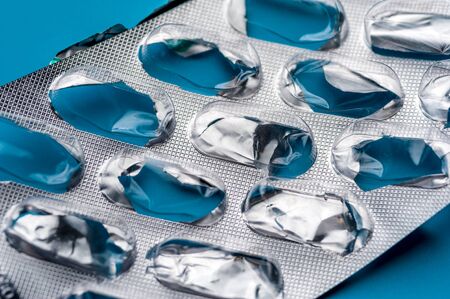 Close-up - Empty Blisters of pills on blue background. Pharmacy, medicine, healthcare concept.の写真素材